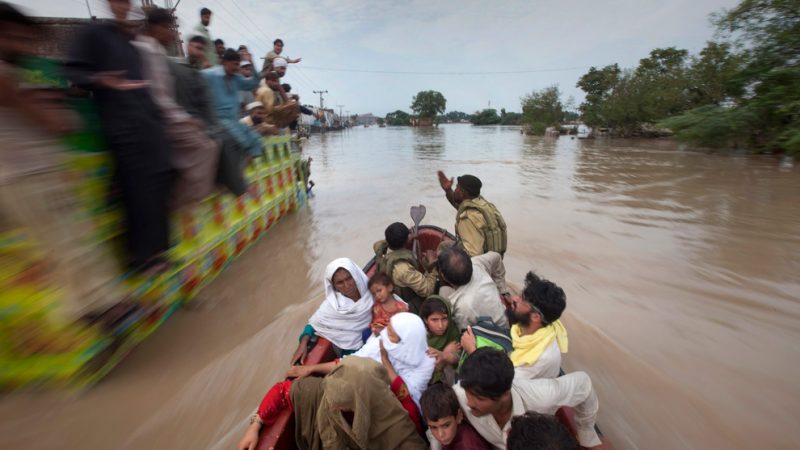 A family being rescued by army soldiers passes a cargo truck with men on top taking shelter from heavy floods in Nowshera, Pakistan on July 31, 2010. (REUTERS/Adrees Latif)